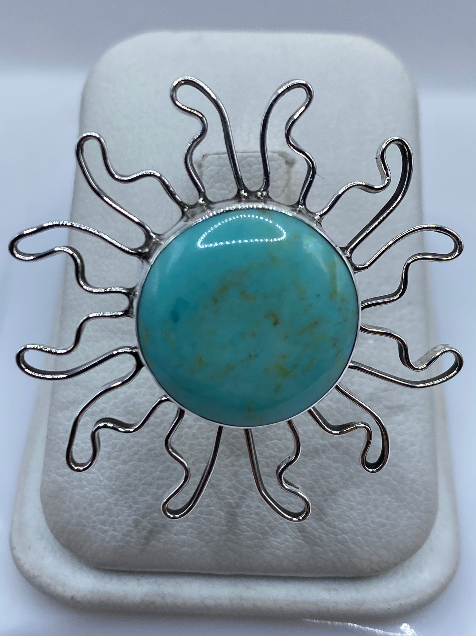 Anillo solar de plata .925 con turquesa azul cielo engastada, rayos ondulantes en la mano