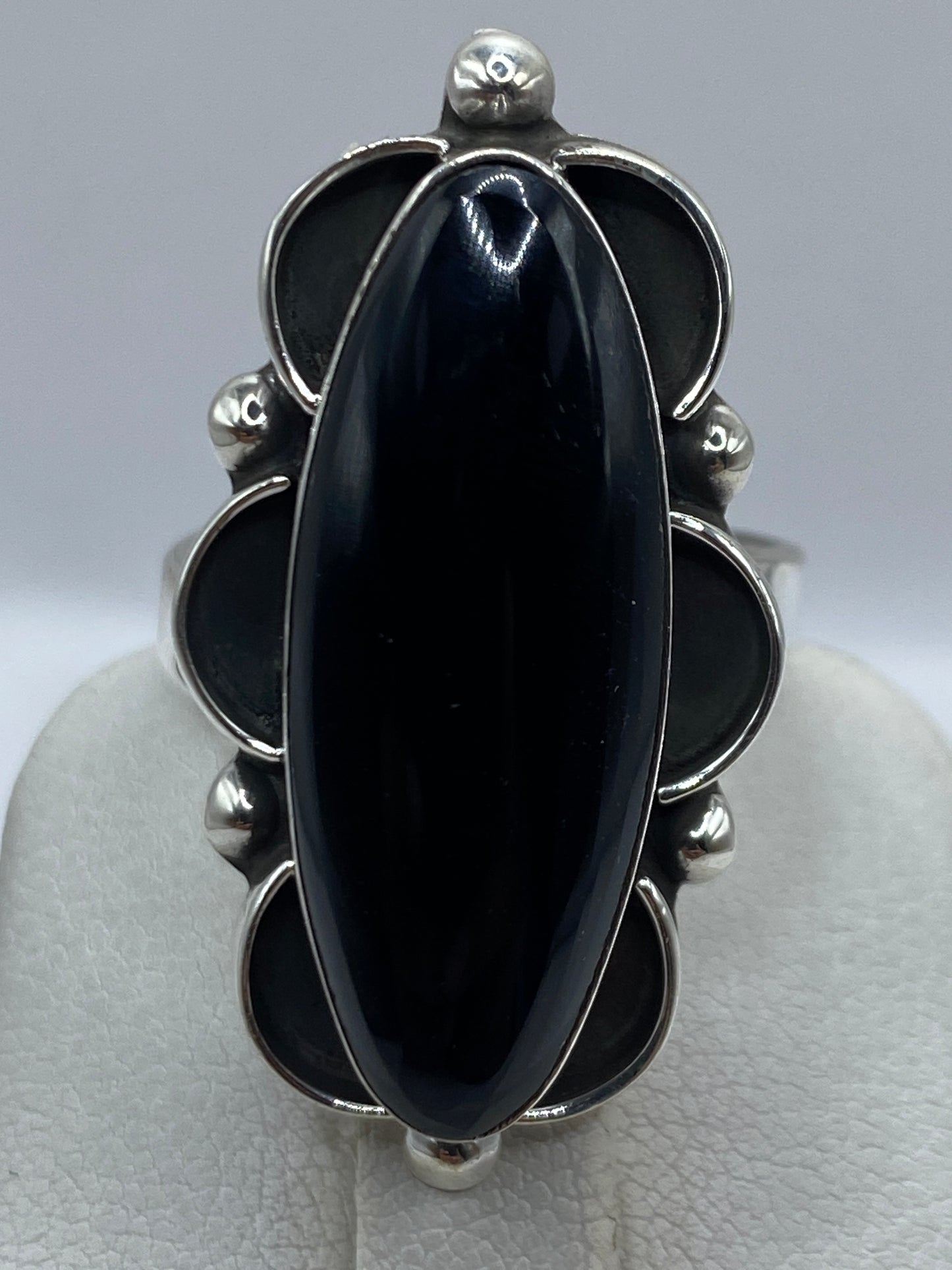 Anillo de ónix puesto en dedo, mostrando el volumen y brillo de la piedra negra