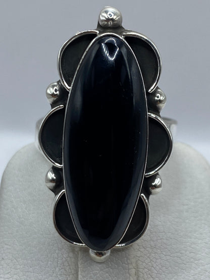 Anillo de ónix puesto en dedo, mostrando el volumen y brillo de la piedra negra