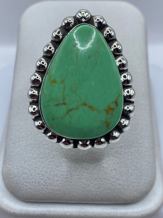 Anillo de plata ajustable con piedra verde engastada, visto desde arriba sobre fondo blanco
