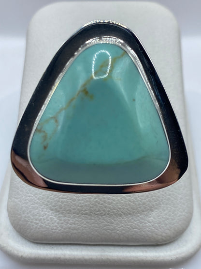 Anillo ajustable de plata con turquesa azul cielo engastada, vista superior en estuche blanco