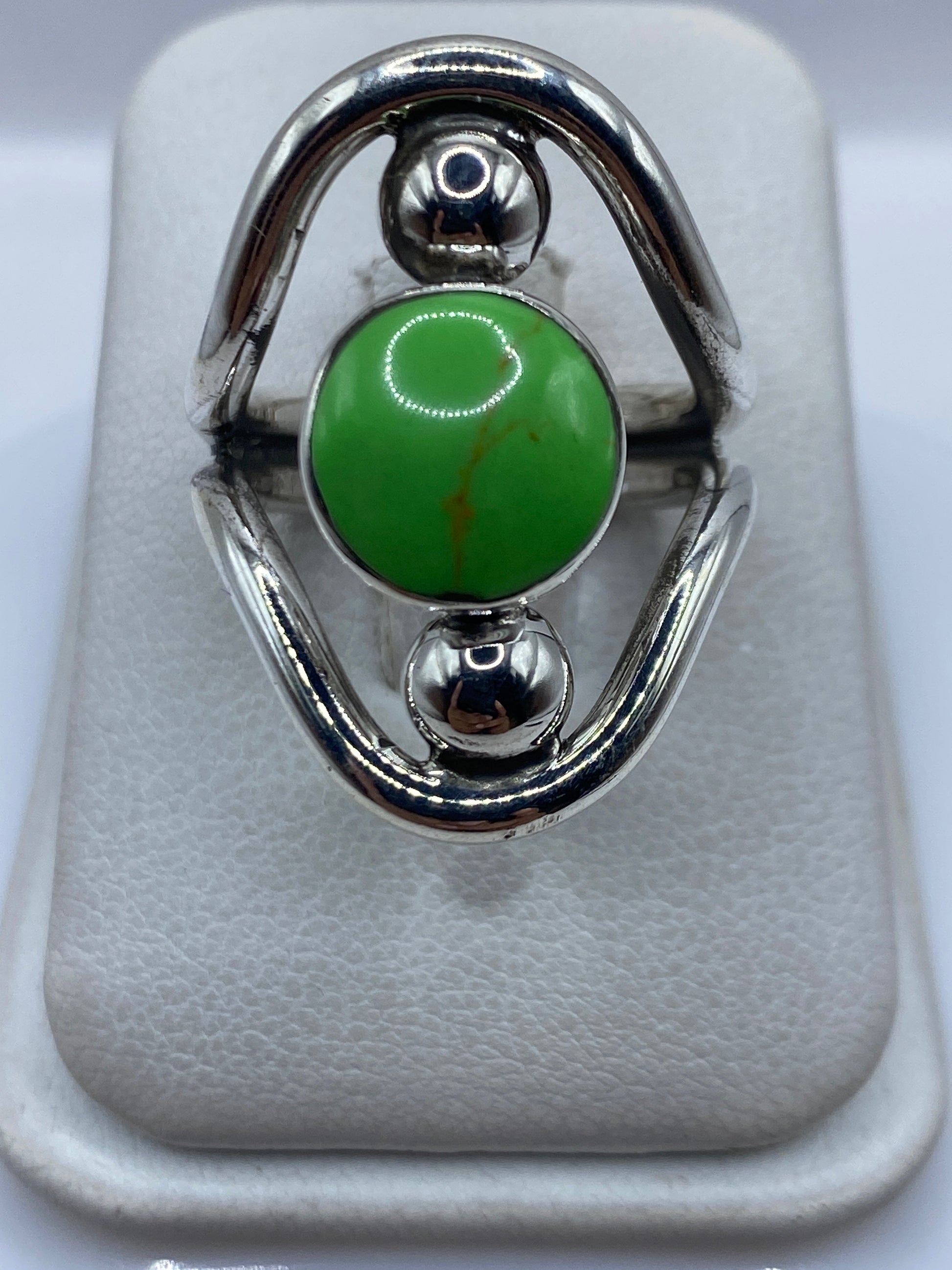 Anillo de plata .925 con piedra verde engastada, visto de frente mostrando las esferas de plata