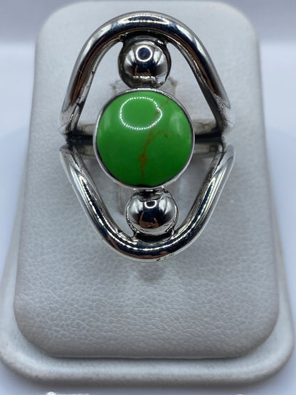 Anillo de plata .925 con piedra verde engastada, visto de frente mostrando las esferas de plata