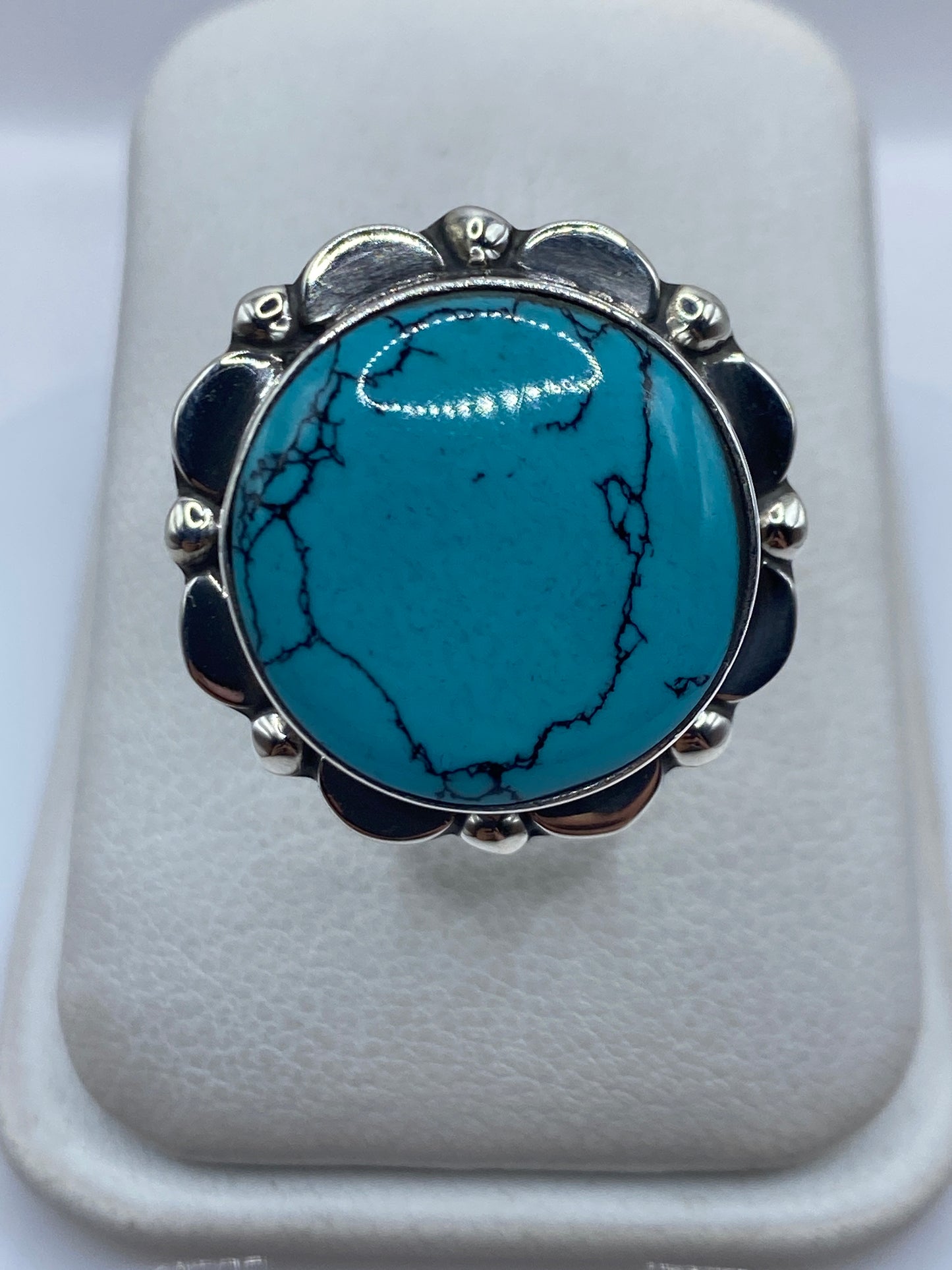 Anillo de plata con turquesa azul verdosa en arco ornamental, vista frontal sobre fondo blanco