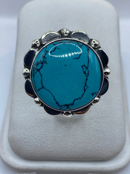Anillo de plata con turquesa azul verdosa en arco ornamental, vista frontal sobre fondo blanco
