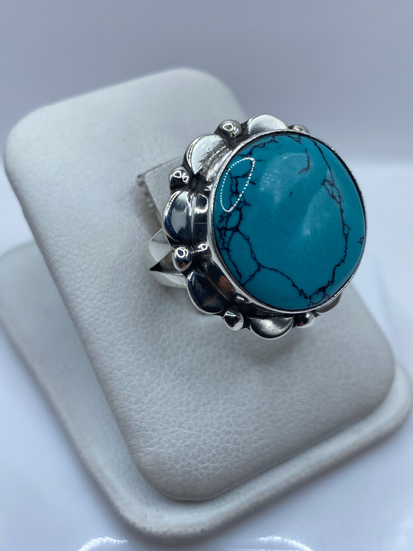 Anillo de turquesa y plata .925 en la mano de una mujer mostrando el engaste de piedra