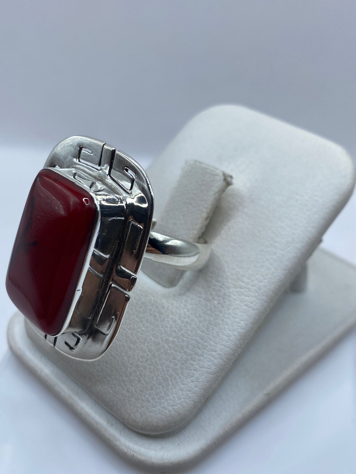 Detalle lateral del anillo mostrando el engaste de coral y la banda de plata .925