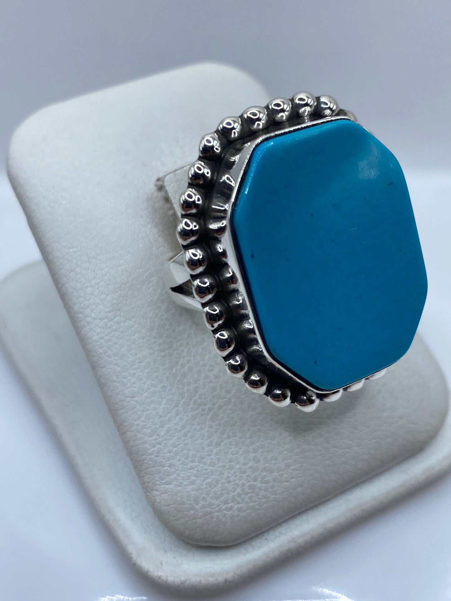 Anillo de turquesa azul en vista lateral mostrando el engaste a mano y el diseño de granulado