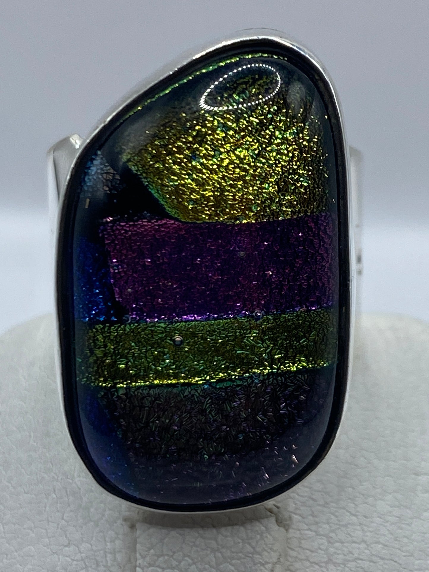 Anillo colocado en el dedo mostrando la incrustación de piedra multicolor en uso