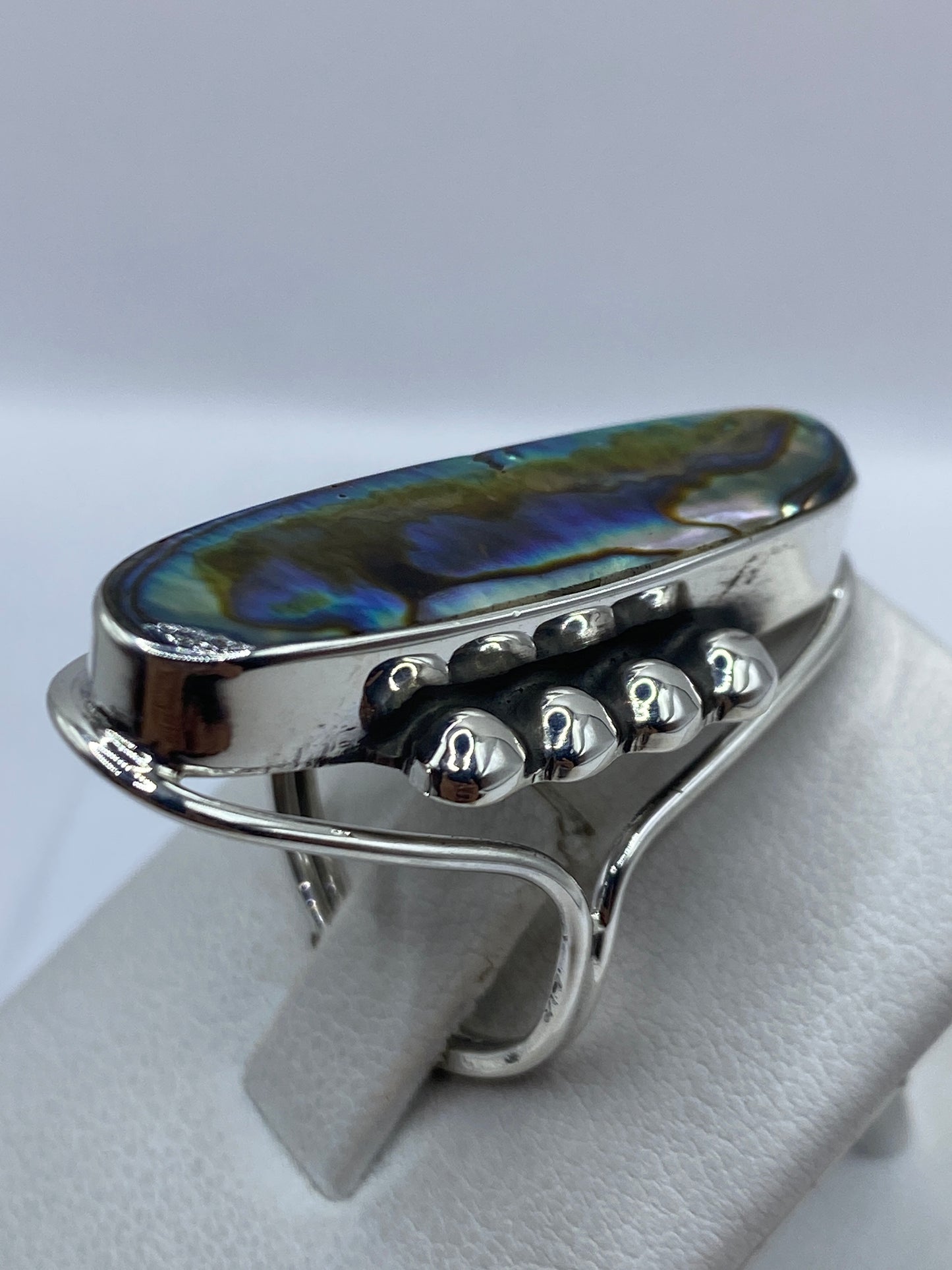 Anillo en dedo, piedra brillante reflejando luz azul y verde