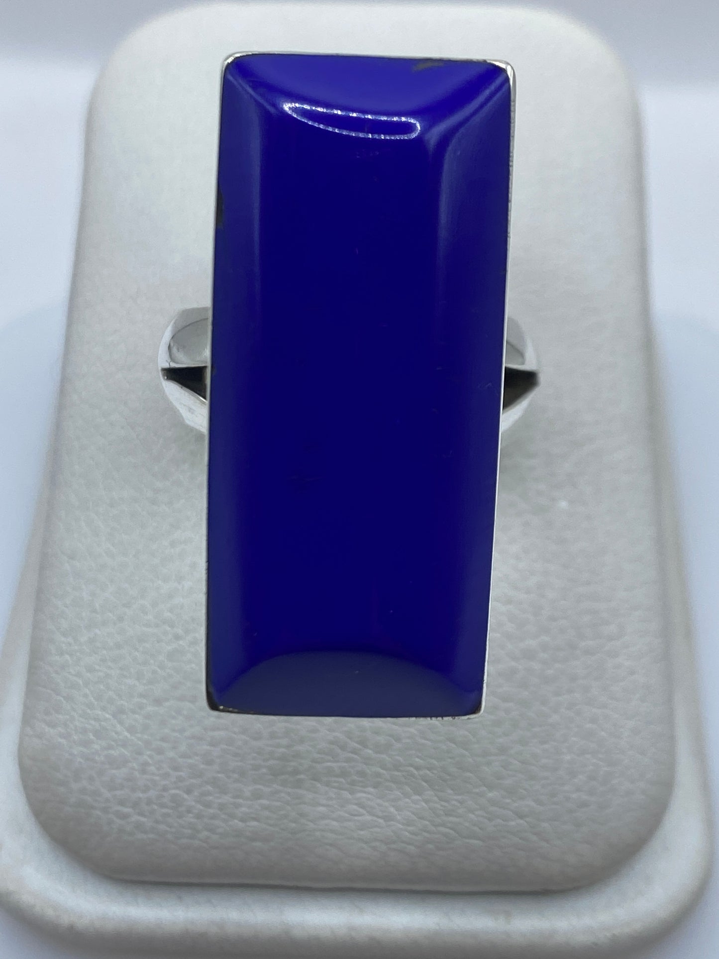 Anillo de plata con piedra azul rectangular en mano de mujer