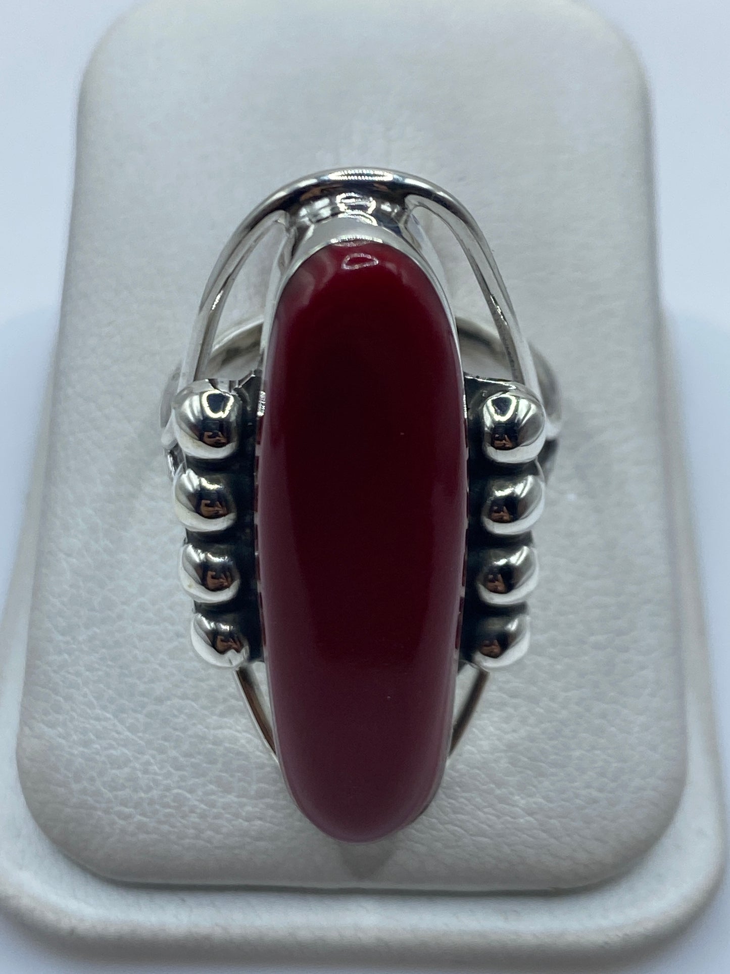 Anillo de plata .925 con piedra roja engastada, vista frontal sobre almohadilla blanca