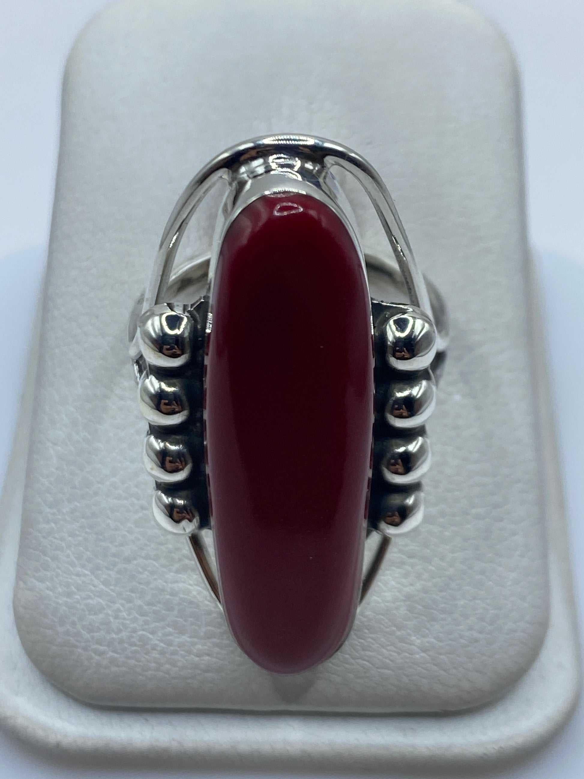 Anillo de plata .925 con piedra roja engastada, vista frontal sobre almohadilla blanca