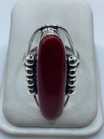 Anillo de plata .925 con piedra roja engastada, vista frontal sobre almohadilla blanca