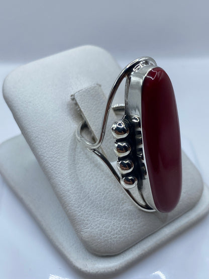 Detalle lateral del anillo mostrando el engaste de la piedra roja y la plata pulida