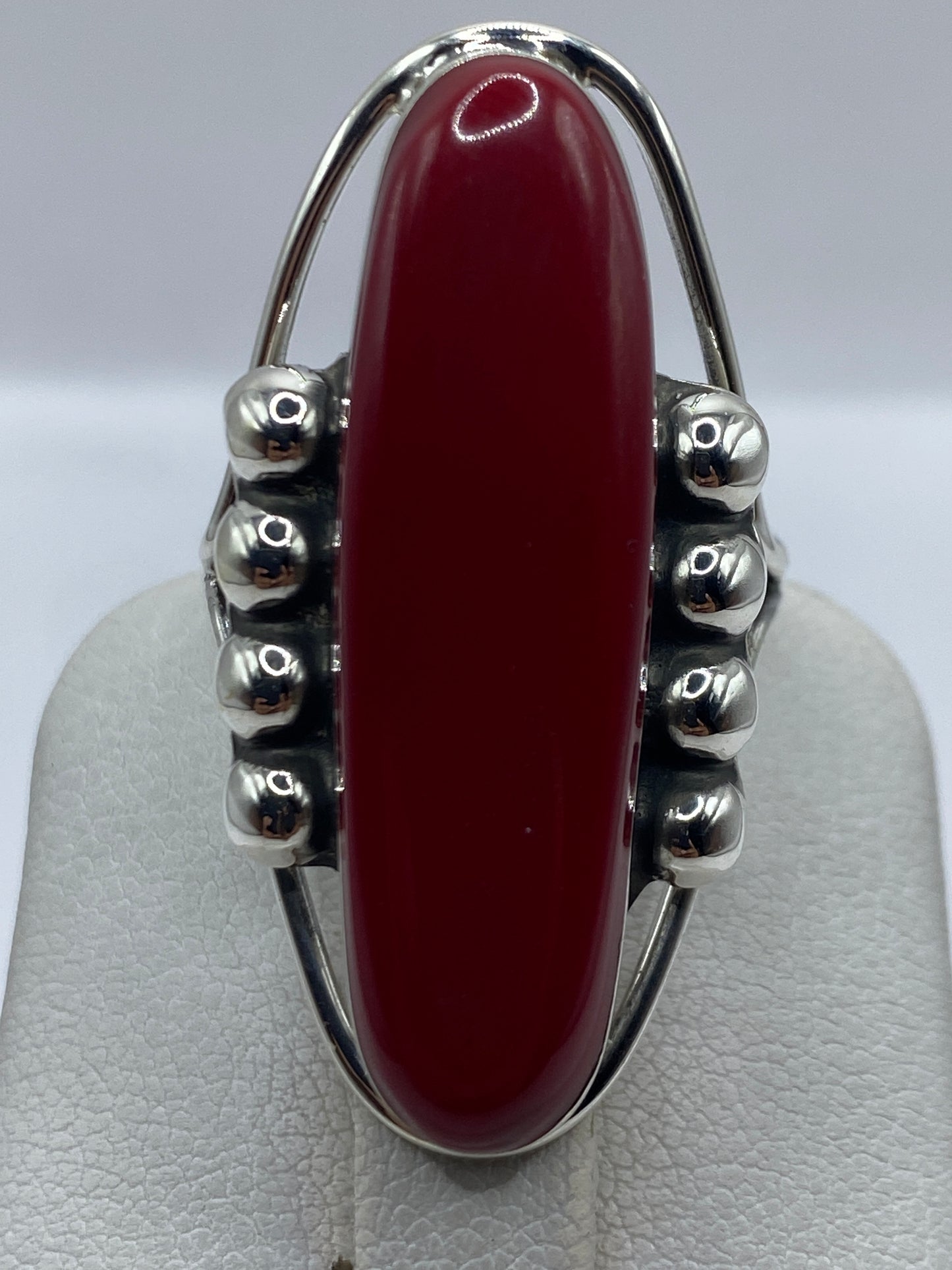 Anillo en la mano mostrando el color rojo profundo de la piedra y el brillo de la plata