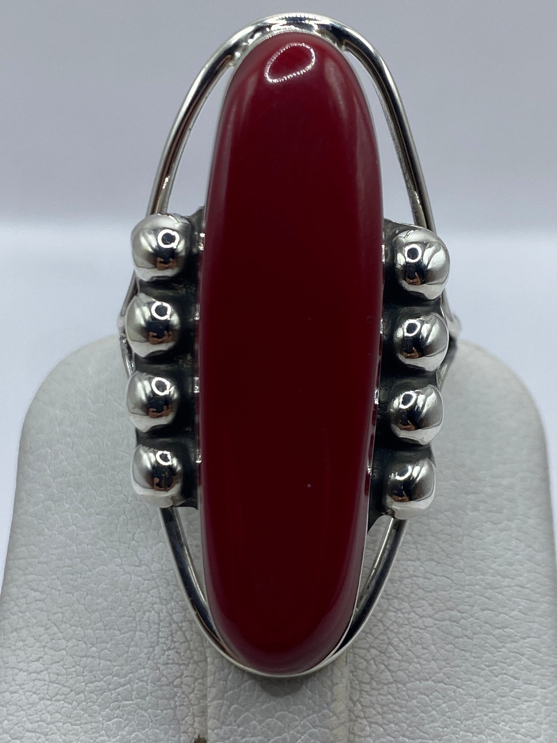 Anillo en la mano mostrando el color rojo profundo de la piedra y el brillo de la plata