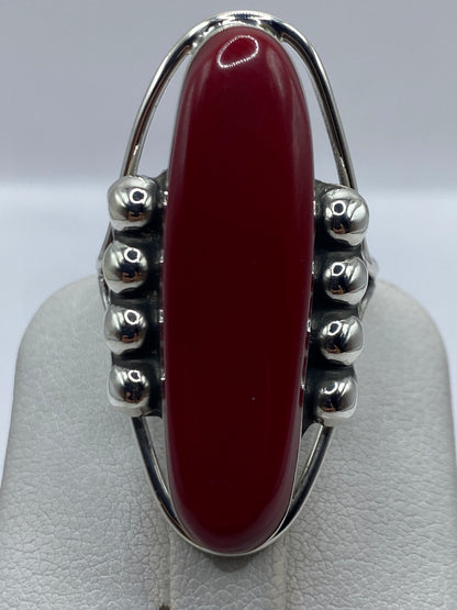 Anillo en la mano mostrando el color rojo profundo de la piedra y el brillo de la plata