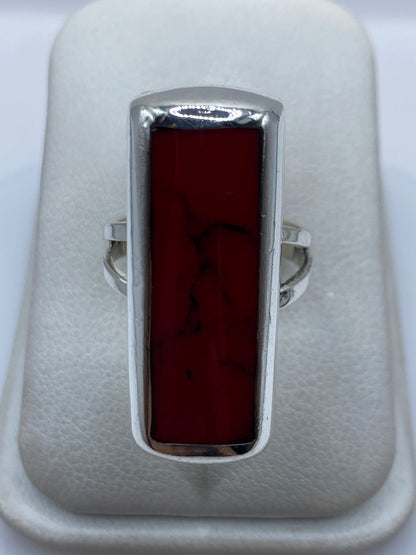 Anillo de plata con coral rojo engastado en marco rectangular, visto de frente sobre fondo blanco