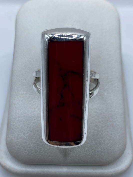 Anillo de plata con coral rojo engastado en marco rectangular, visto de frente sobre fondo blanco