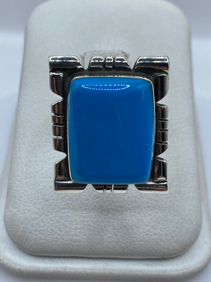 Anillo de plata ajustable con piedra azul en marco arquitectónico, vista frontal sobre fondo blanco