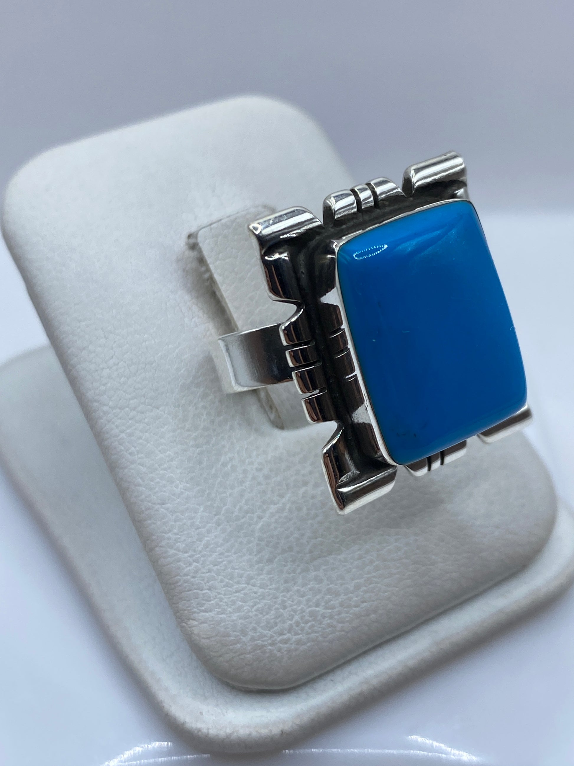 Anillo de plata .925 con piedra azul engastada a mano, vista lateral mostrando el diseño tallado