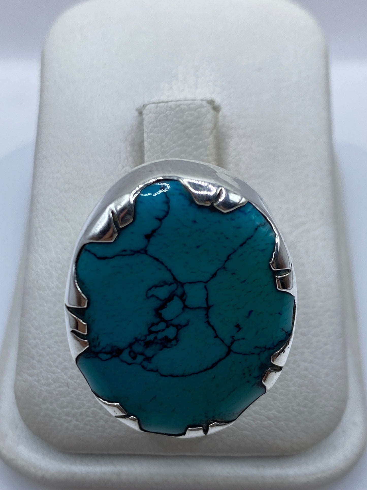Anillo de plata con turquesa azul cielo en mano de mujer, mostrando el engaste metálico
