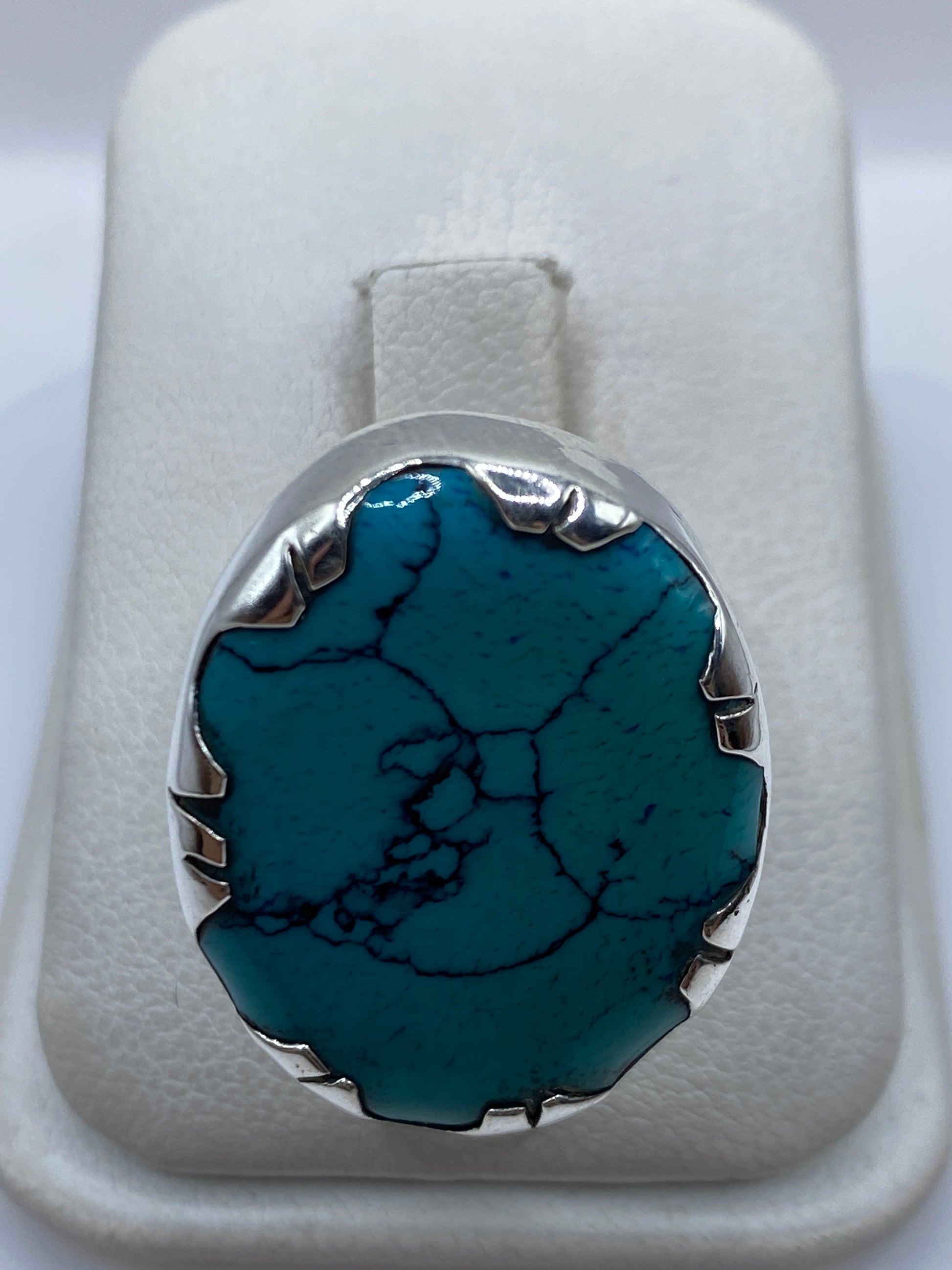 Anillo de plata con turquesa azul cielo en mano de mujer, mostrando el engaste metálico