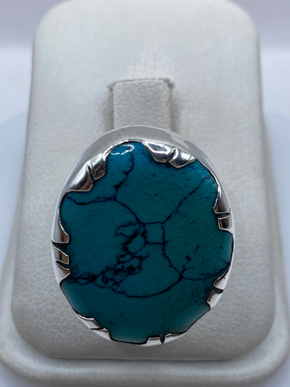Anillo de plata con turquesa azul cielo en mano de mujer, mostrando el engaste metálico