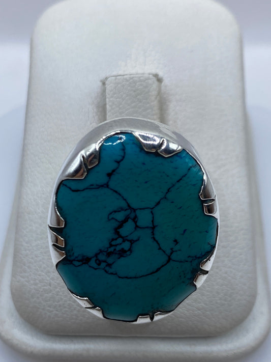 Anillo de plata con turquesa azul cielo en mano de mujer, mostrando el engaste metálico