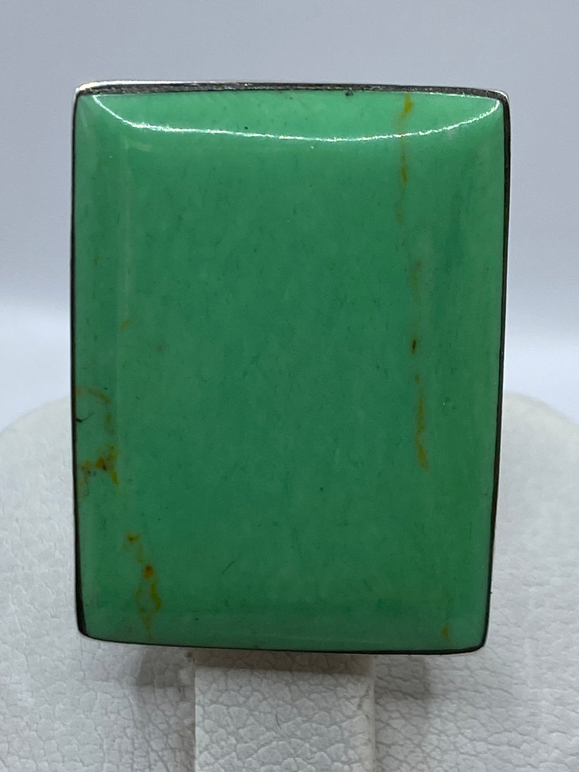Anillo de plata con piedra verde sobre dedo, con luz natural