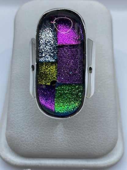 Anillo de plata multicolor con compartimentos de púrpura, verde, azul y plateado en mano de mujer