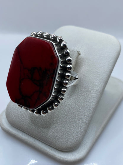Anillo de plata coral rojo en la mano, mostrando el marco de bolitas de plata