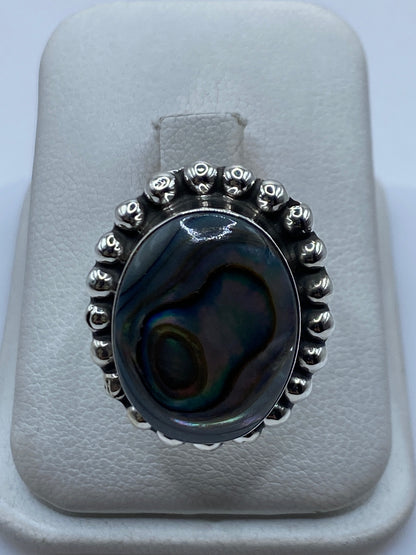 Anillo de plata ajustable con piedra iridiscente que brilla en azul, verde y dorado