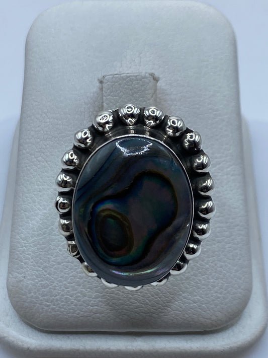 Anillo de plata ajustable con piedra iridiscente que brilla en azul, verde y dorado