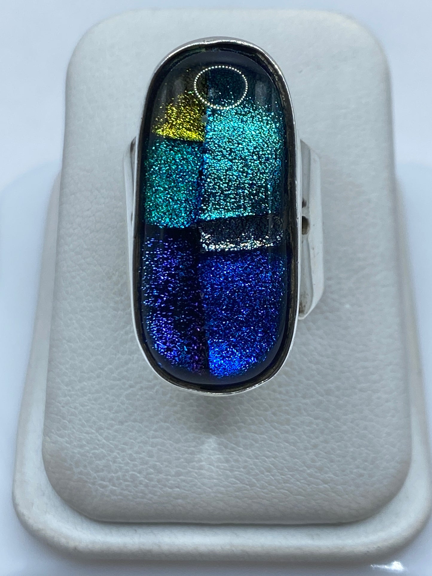 Anillo de plata geométrico multicolor con tonos azul, turquesa, amarillo y negro en una mano