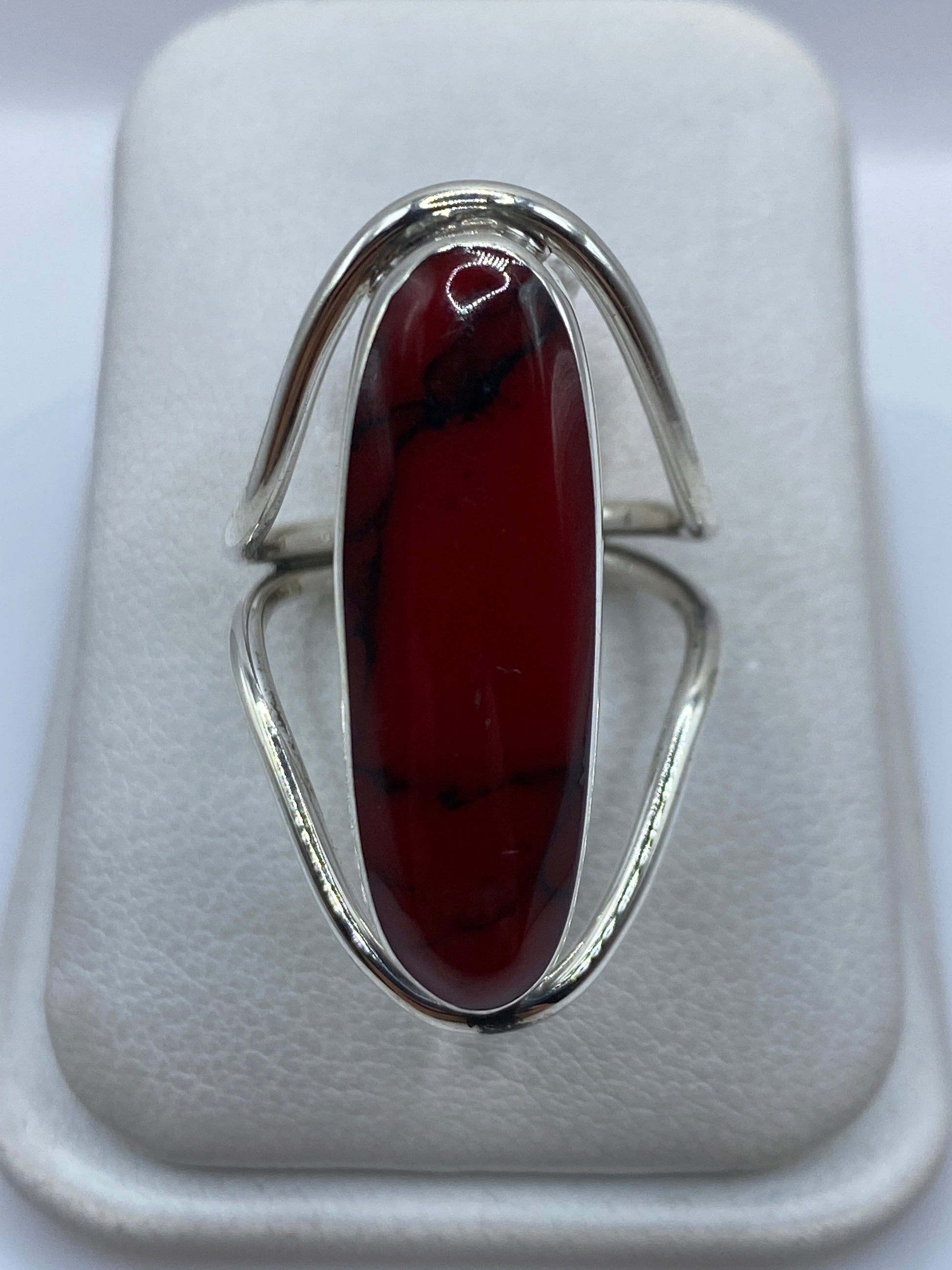 Anillo de plata con coral rojo ovalado en la mano, vista frontal