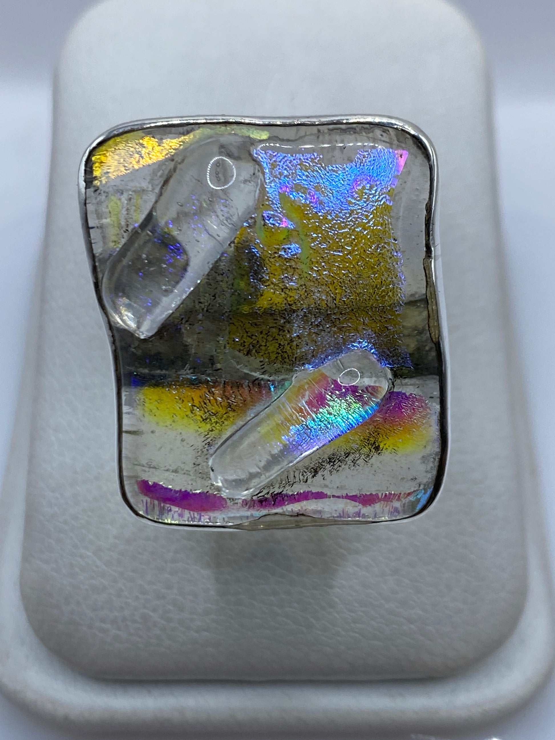 Anillo ajustable de plata .925 con resina iridiscente mostrando reflejos azules, púrpuras y verdes
