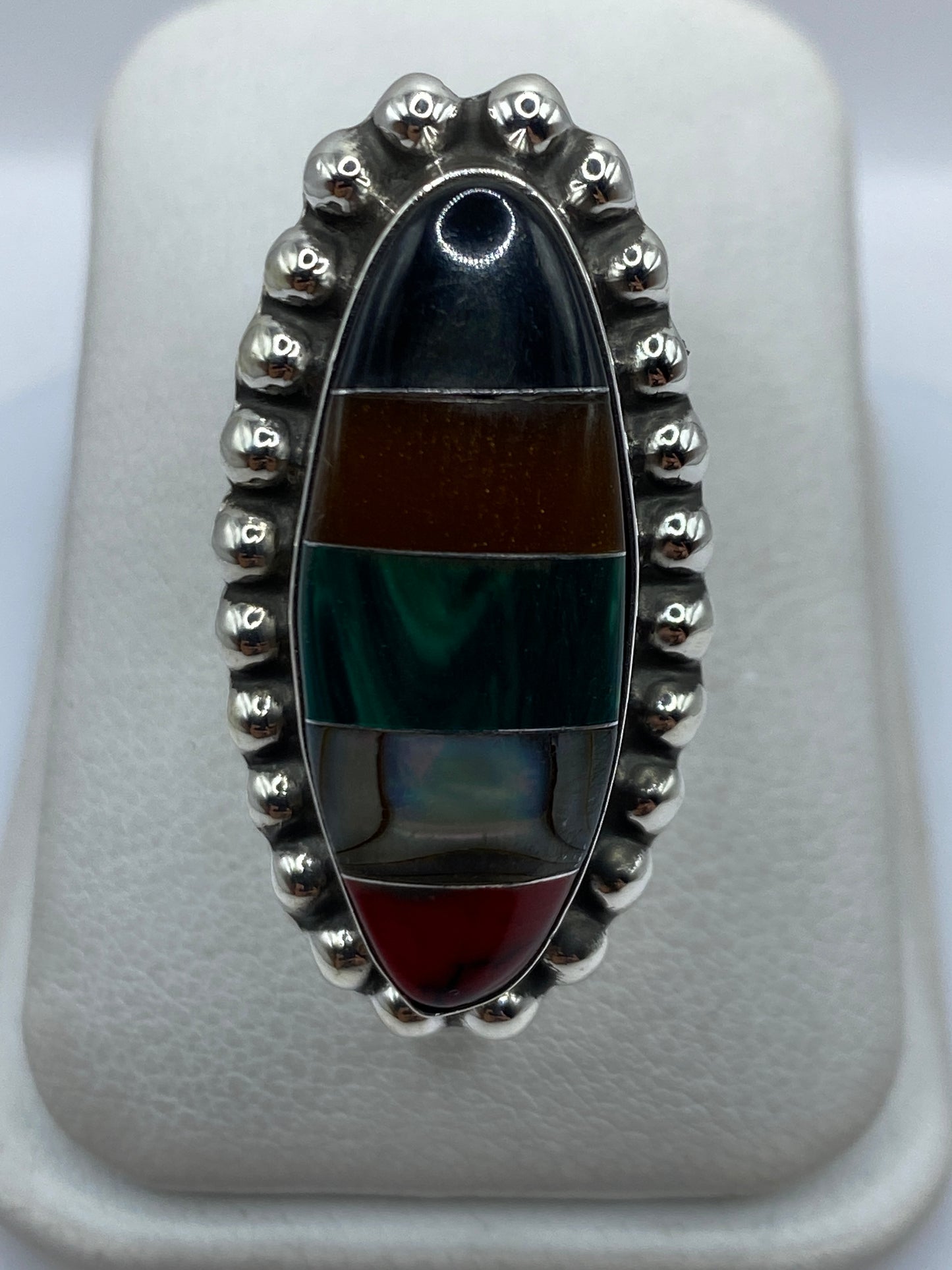 Anillo ajustable de plata con malaquita verde engastada, visto de frente sobre estuche blanco