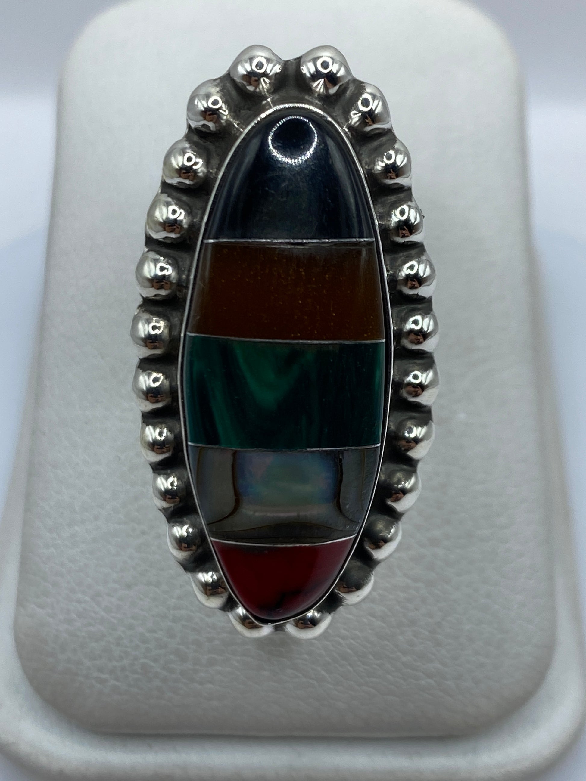 Anillo ajustable de plata con malaquita verde engastada, visto de frente sobre estuche blanco