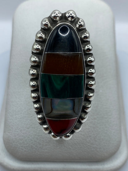 Anillo ajustable de plata con malaquita verde engastada, visto de frente sobre estuche blanco