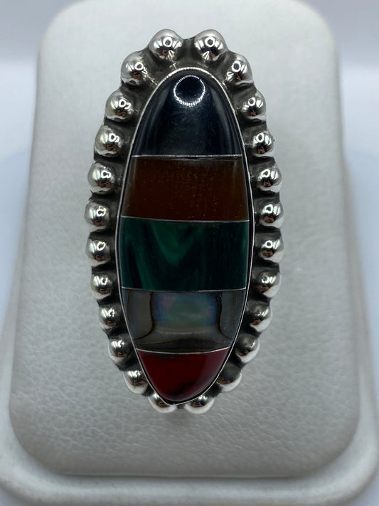 Anillo ajustable de plata con malaquita verde engastada, visto de frente sobre estuche blanco