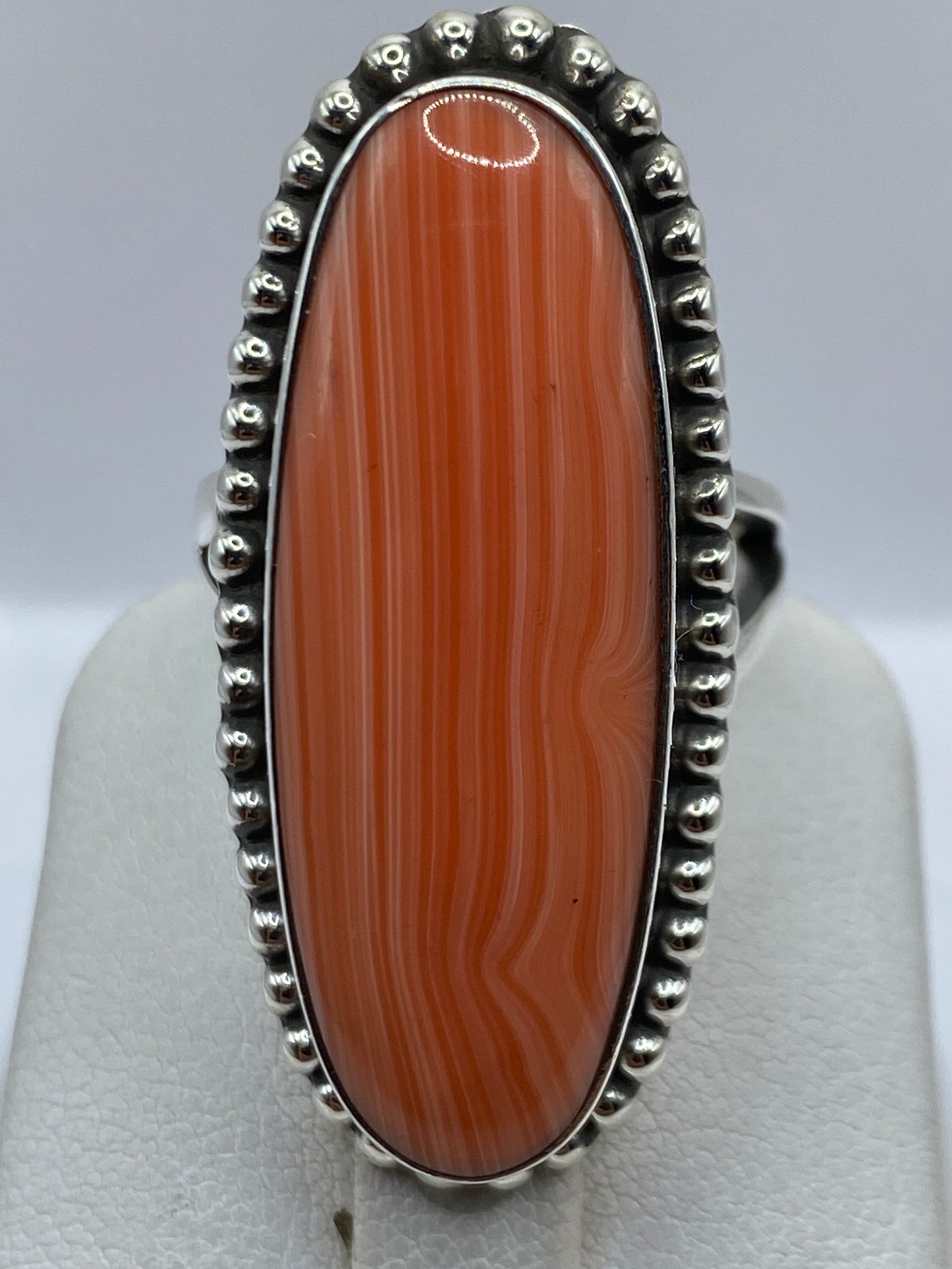 Anillo de coral engastado a mano en dedo de mujer, tonos cálidos