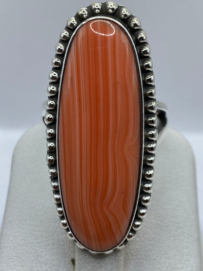 Anillo de coral engastado a mano en dedo de mujer, tonos cálidos