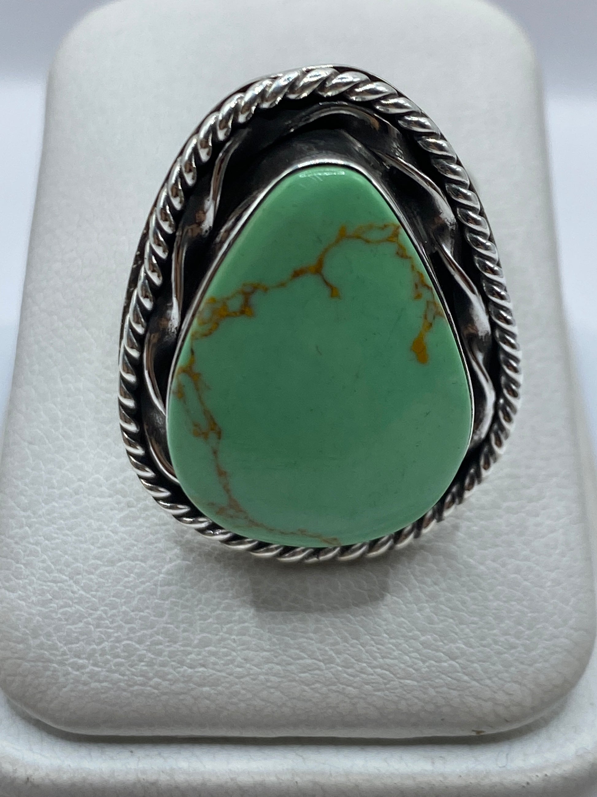 Anillo de plata ajustable con piedra verde engastada en la mano de una mujer