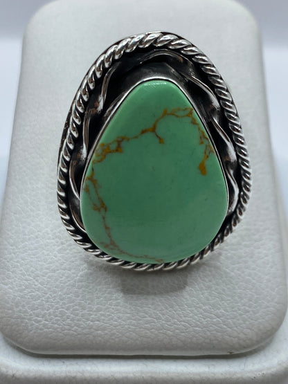Anillo de plata ajustable con piedra verde engastada en la mano de una mujer