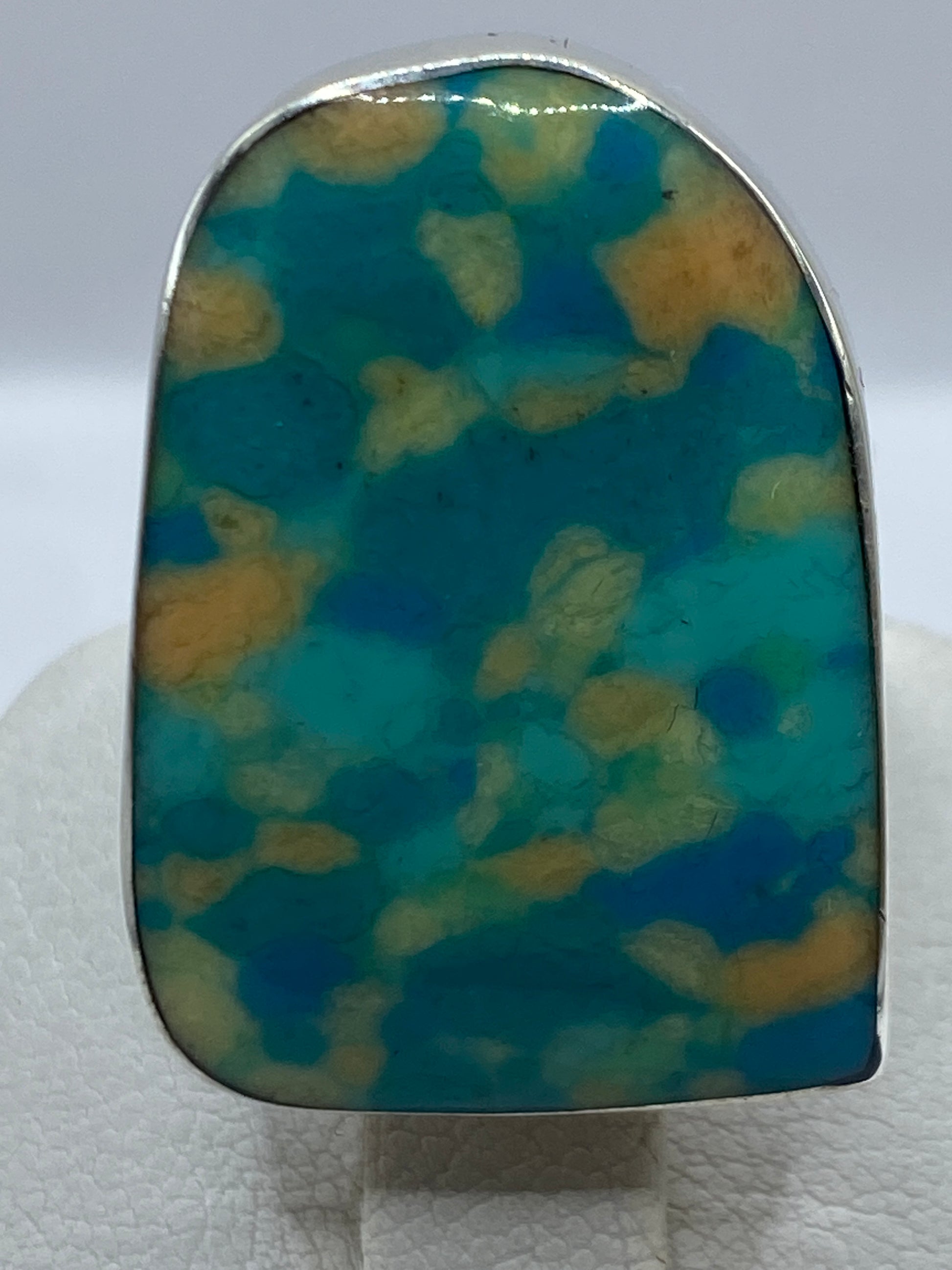 Anillo puesto en mano femenina destacando los tonos multicolor de la gema