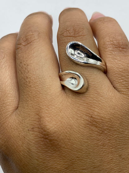 Anillo ajustable sobre fondo gris, mostrando el acabado pulido brillante