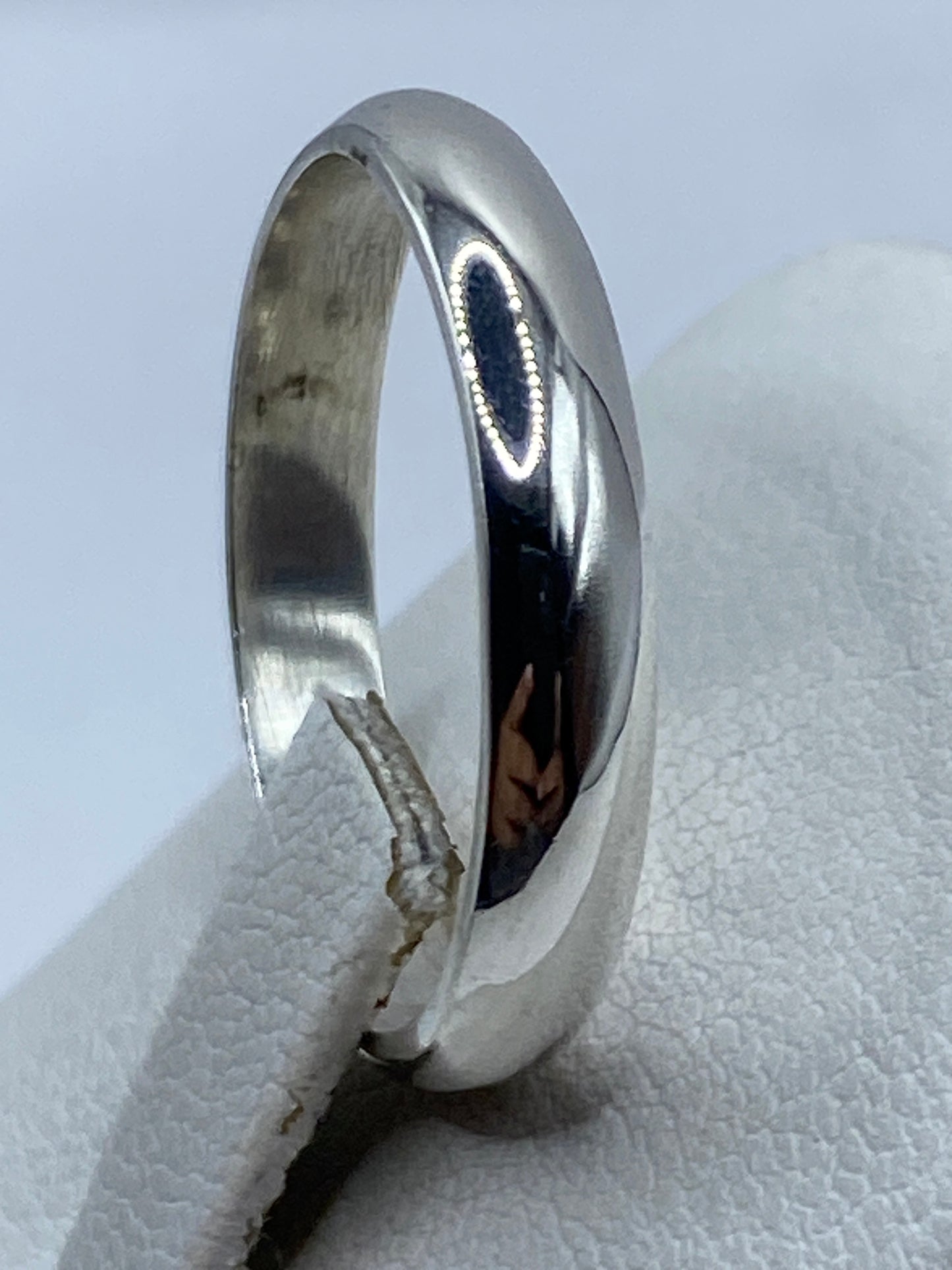 Anillo de plata en el dedo mostrando su acabado espejo y ligereza