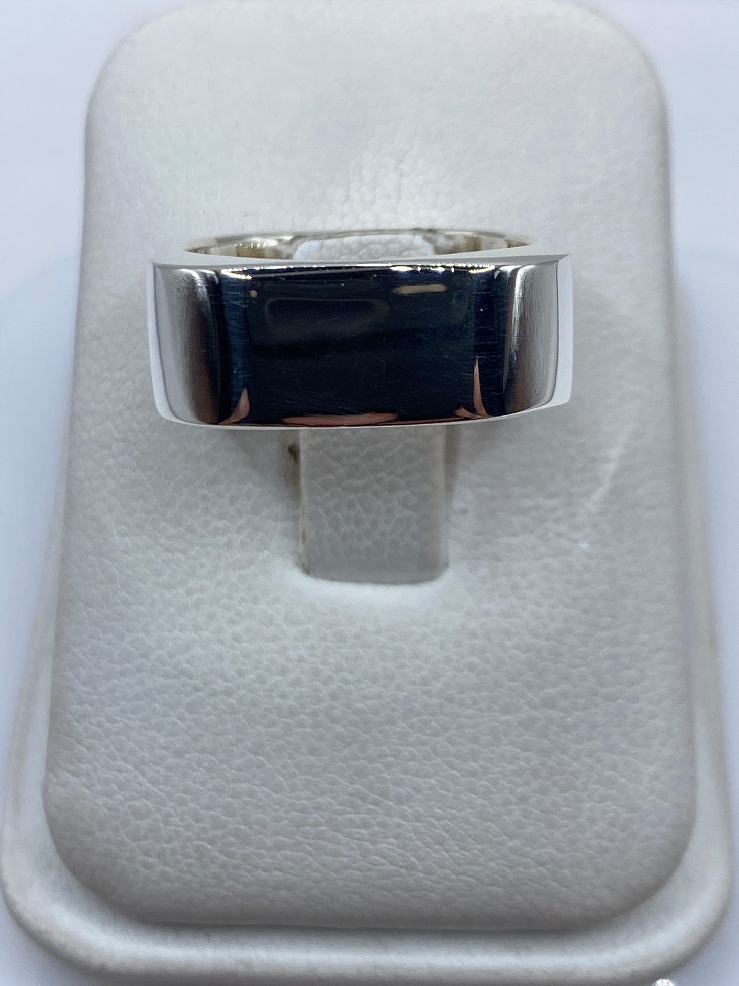 Anillo de plata cartoneado minimalista en dedo de mujer, vista frontal